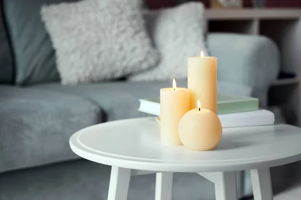 Belles bougies allumées avec des livres sur table blanche à l'intérieur — Photo