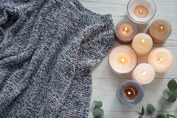Velas ardentes bonitas com suéter quente na mesa de madeira branca — Fotografia de Stock