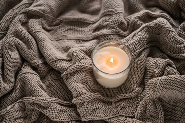 Beautiful burning candle on warm plaid — Stock Photo, Image