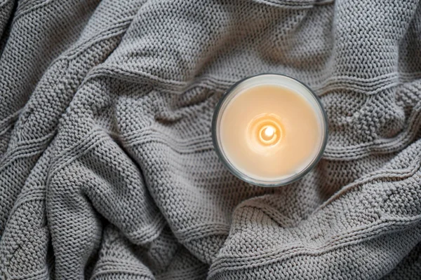 Schöne brennende Kerze auf warmem Plaid — Stockfoto