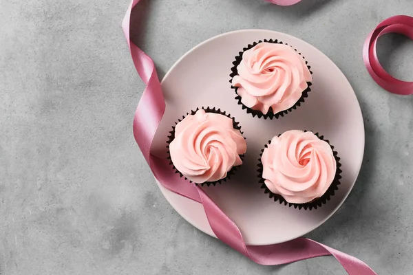 Teller mit leckeren Cupcakes auf grauem Tisch — Stockfoto