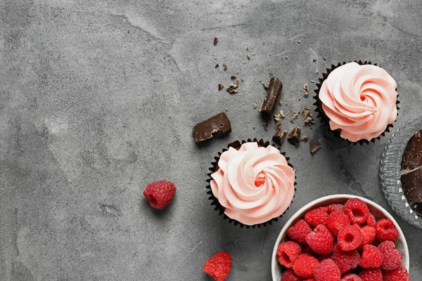 Doces cupcakes, framboesa e chocolate na mesa cinza — Fotografia de Stock