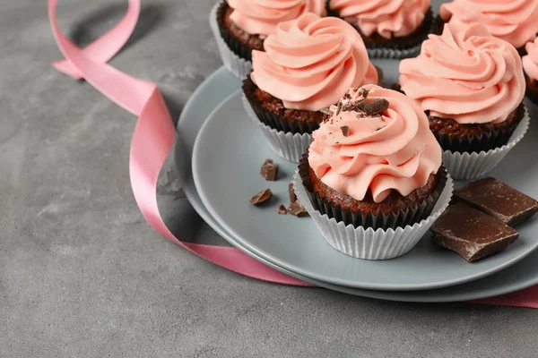 Placa con magdalenas dulces y chocolate sobre mesa gris —  Fotos de Stock