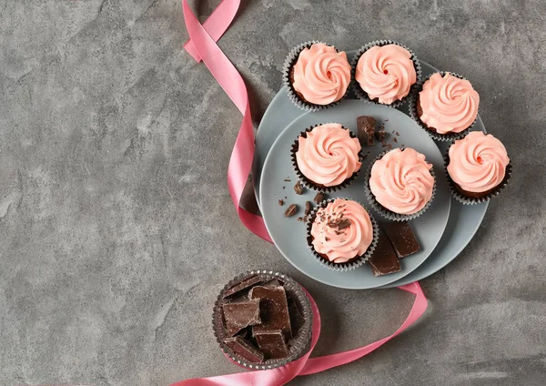 Doces cupcakes e chocolate na mesa cinza — Fotografia de Stock