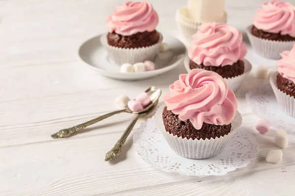 Doces cupcakes com marshmallow e colheres na mesa de madeira branca — Fotografia de Stock