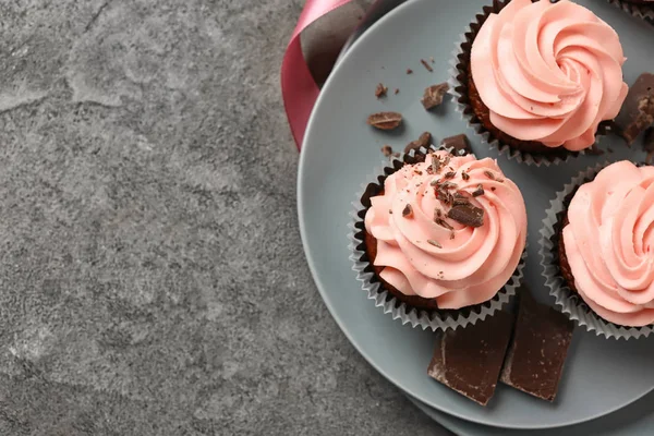 Prato com cupcakes doces e chocolate na mesa cinza — Fotografia de Stock