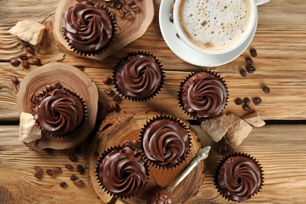 Delicious chocolate cupcakes with cup of coffee on wooden table — Stock Photo, Image