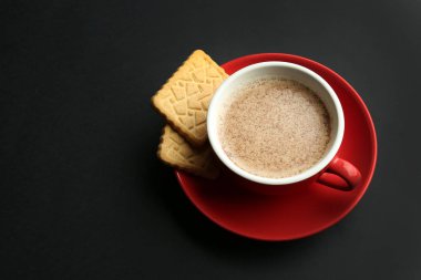 Fincan lezzetli aromatik kahve ve siyah arka plan üzerine çerezler ile