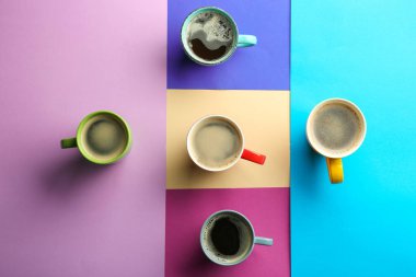 Düz renkli arka plan üzerinde lezzetli aromatik kahve ile fazla bardak yatıyordu