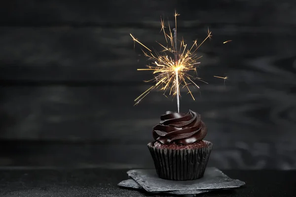 Delicioso cupcake de cumpleaños con espumoso en la mesa oscura — Foto de Stock