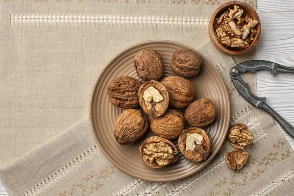 Тарелка с вкусными грецкими орехами и орехами на столе — стоковое фото