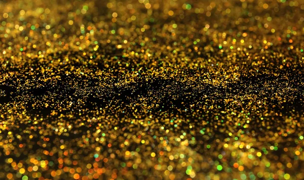 Glanzende gouden glitter op donkere achtergrond — Stockfoto