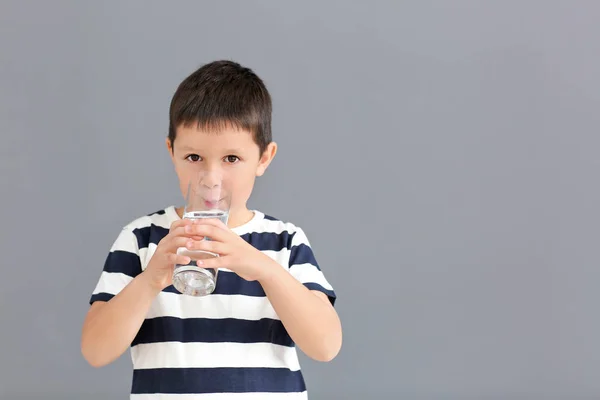 Niño bebiendo agua dulce sobre fondo gris — Foto de Stock