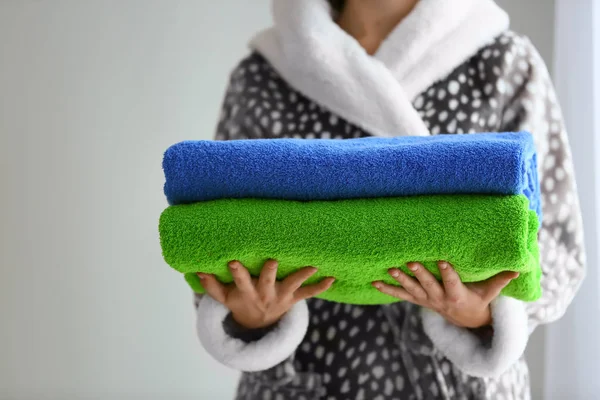 Женщина держит сложенные цветные полотенца на светлом фоне — стоковое фото