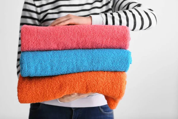 Mulher segurando toalhas de cor dobradas no fundo branco, close-up — Fotografia de Stock