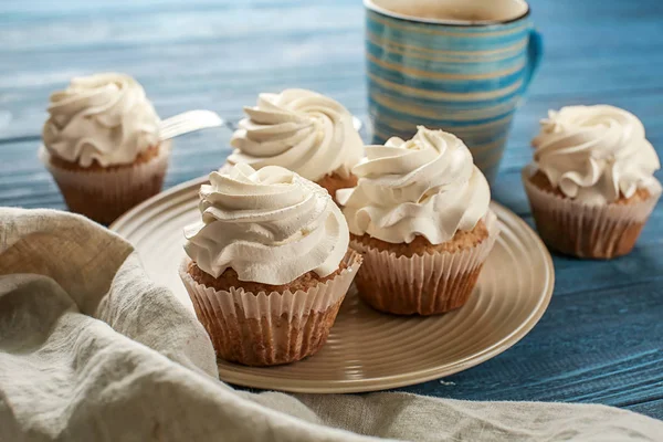 Plate with tasty cupcakes on wooden table — Stock Photo, Image