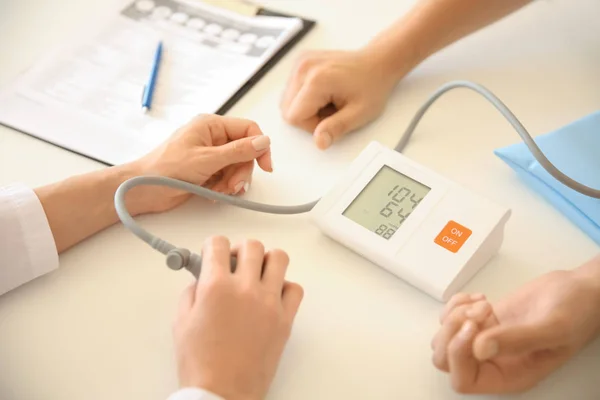 Médico femenino midiendo la presión arterial del paciente masculino en el hospital —  Fotos de Stock