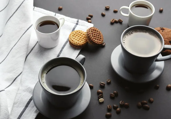 Bekers met smakelijke aromatische koffie en koekjes op tafel — Stockfoto