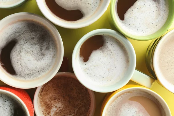 Багато чашок зі смачною ароматичною кавою на кольоровому фоні, вид зверху — стокове фото