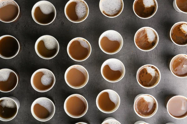 Багато пластикових чашок зі смачною ароматичною кавою на темному фоні, плоска покладена — стокове фото