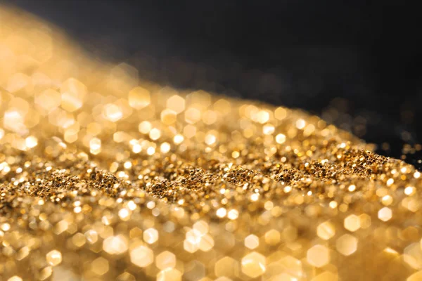 Golden glitters on dark background, closeup — Stock Photo, Image