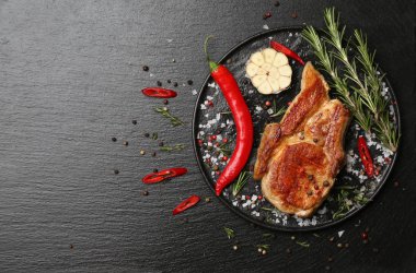 Lezzetli pişmiş et ve baharat koyu arka plan üzerinde plaka