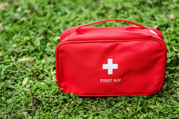 First aid kit on green grass outdoors — Stock Photo, Image