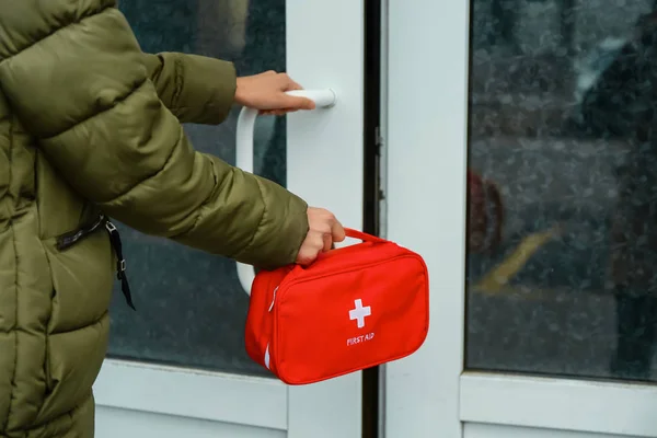 Woman with first aid kit opening door