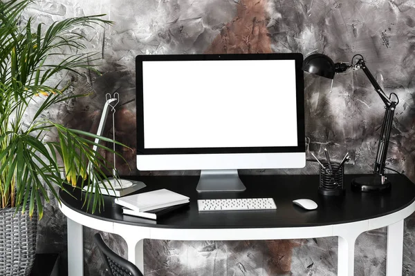 Стильне робоче місце з сучасним комп'ютером біля сірої стіни — стокове фото
