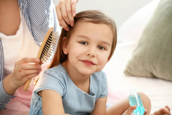 Young mother brushing hair of her cute little daughter at home — Stock Photo, Image