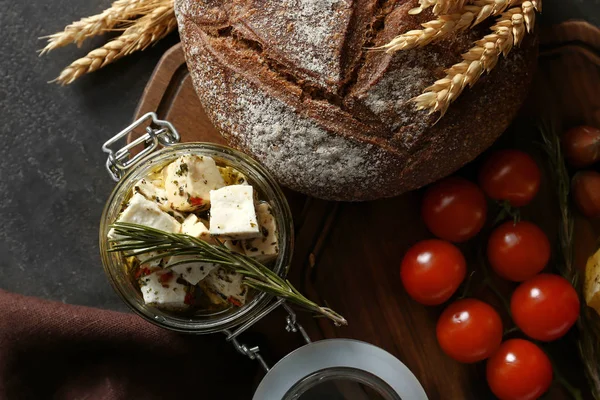 Glazen pot met gemarineerde kaas en lekker brood op houten bord — Stockfoto