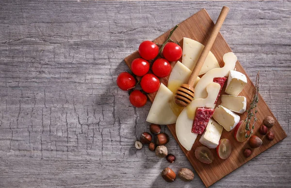 Fából készült fedélzet-val választék, ízletes sajt, paradicsom, méz a táblázat — Stock Fotó