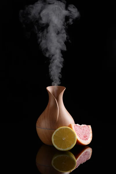 Difusor de óleo de aroma e frutas cítricas em fundo escuro — Fotografia de Stock
