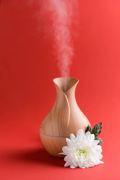 Aroma oil diffuser and flower on color background