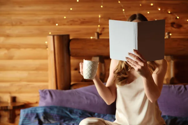 Beautiful woman reading book and drinking coffee in morning at winter resort — Stock Photo, Image