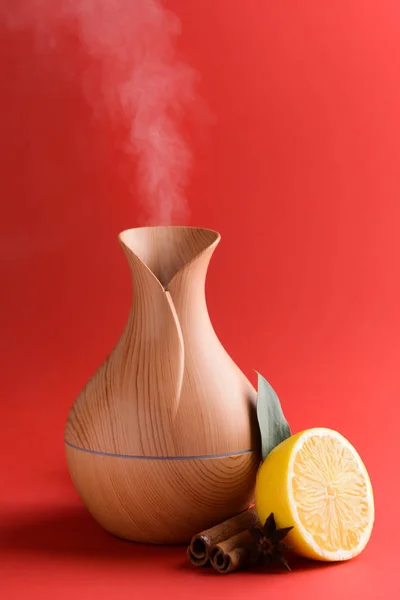 Aroma oil diffuser, lemon and cinnamon on color background
