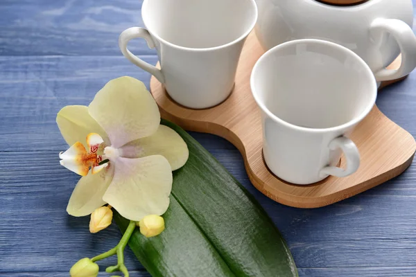 Empty cups and beautiful orchid flower on wooden table — Stock Photo, Image