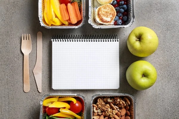 Containers with delicious food and blank notebook on grey background — Stock Photo, Image