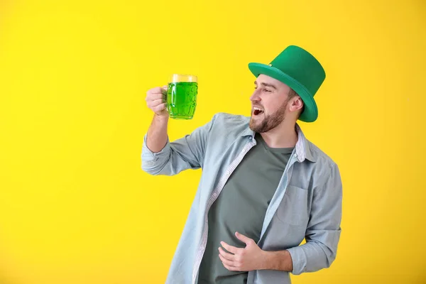 Bello giovanotto in cappello verde e con tazza di birra sullo sfondo a colori. Festa di San Patrizio — Foto Stock