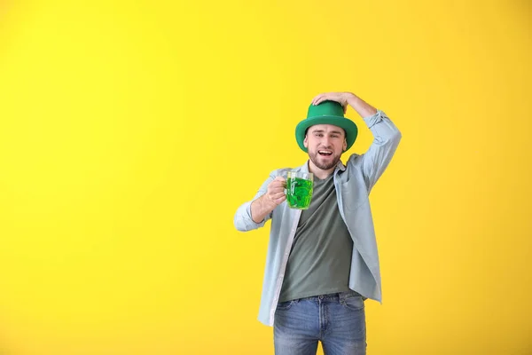 Joven guapo en sombrero verde y con jarra de cerveza sobre fondo de color. Celebración del Día de San Patricio — Foto de Stock