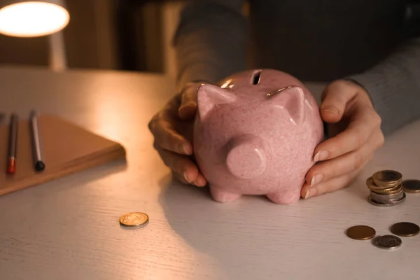 Woman with piggy bank at table. Concept of savings