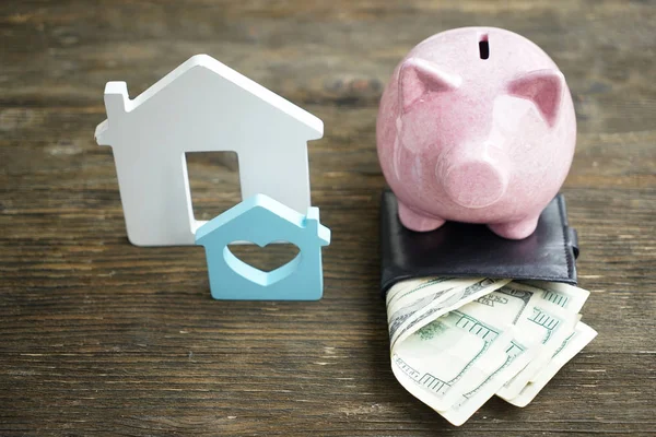 Sparschwein, Geldbörse mit Dollarnoten und Figur in Form eines Hauses auf dem Tisch. Konzept des Sparens für den Kauf eines neuen Hauses — Stockfoto