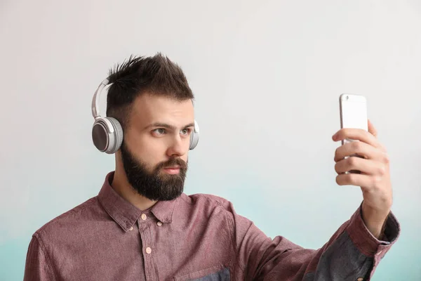 Mladý muž pořizování selfie s mobilním telefonem proti bílým pozadím — Stock fotografie