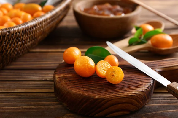 Dřevěná deska s lahodnou kumquat ovoce na stole — Stock fotografie