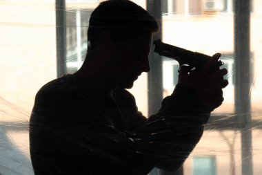 Pencere yakınında intihar etmek için silah gidiyor genç adam silüeti