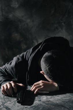 Masadaki silahla depresif genç adam. İntihar farkındalık kavramı