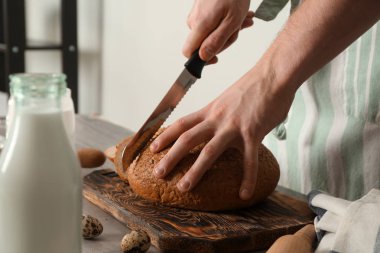 Adam mutfakta, closeup taze pişmiş ekmek kesme