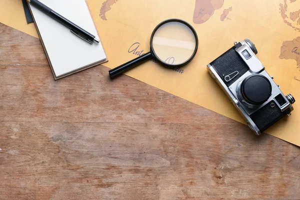 Notebook, magnifier, photo camera and world map on wooden background. Travel concept — Stock Photo, Image