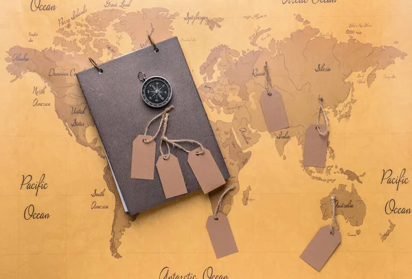 Notebook, compass and tags on world map. Travel concept — Stock Photo, Image