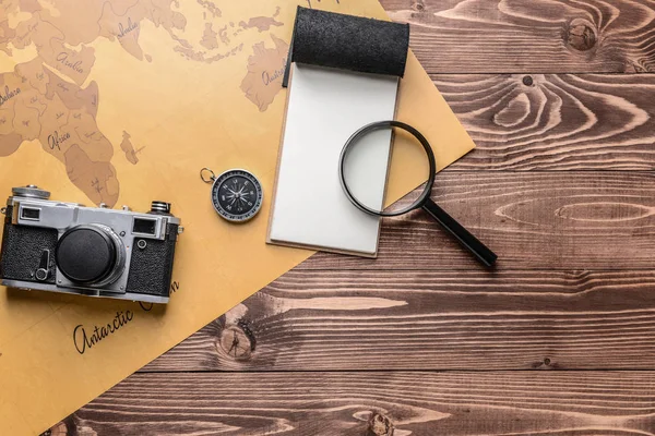Notebook, lupa, bússola, câmera de foto e mapa do mundo em fundo de madeira. Conceito de viagem — Fotografia de Stock